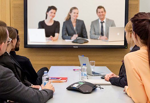 People sitting at boardroom table watching a presentation