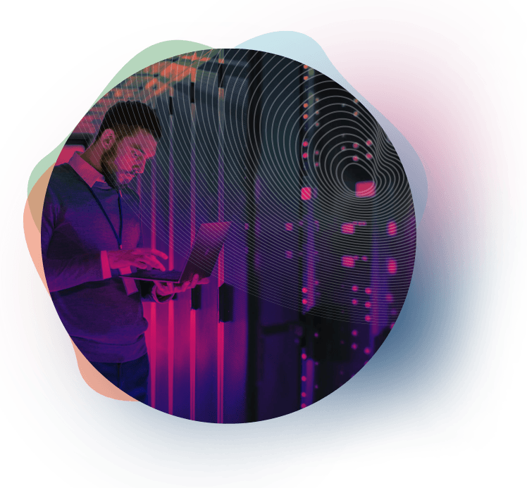 Man using a laptop in a server room with pink and purple lighting.