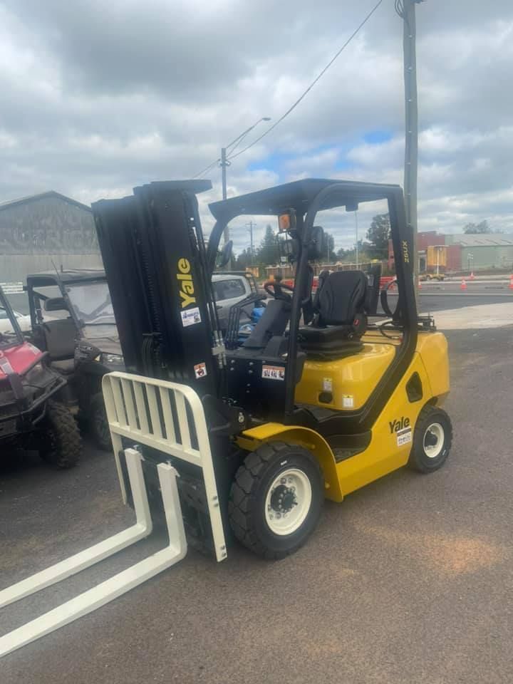 Yellow Yale forklift with white forks, parked outdoors.