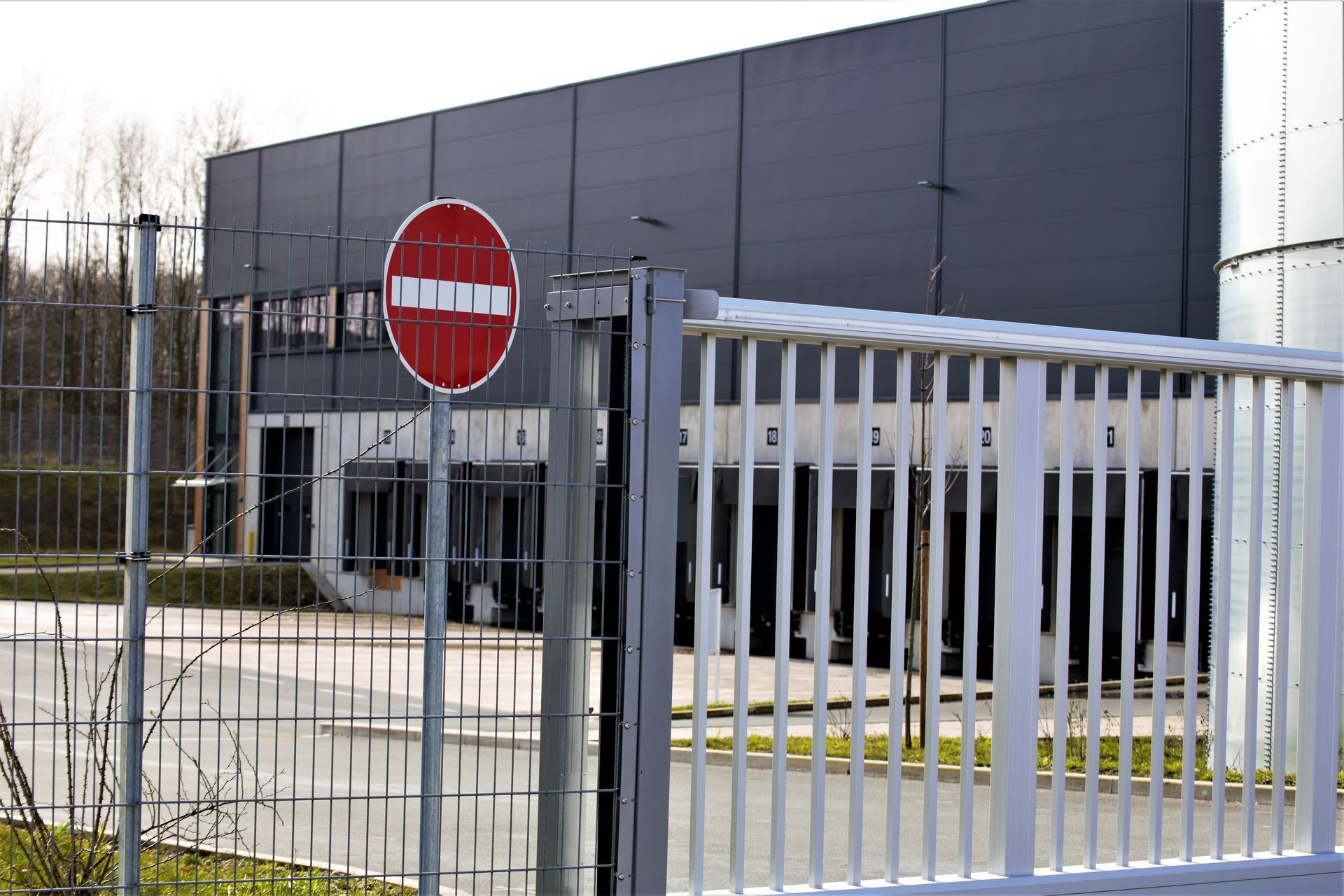Industrial facility entrance with metal gate, fence, and no-entry traffic sign Industrial facility entrance with metal gate, fence, and no-entry traffic sign