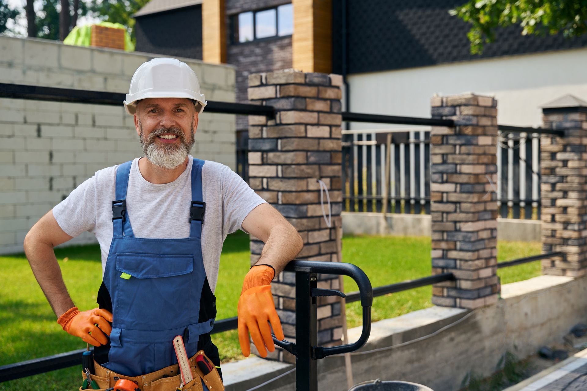 Contractor in safety gear standing beside a residential metal fence installation Contractor in safety gear standing beside a residential metal fence installation