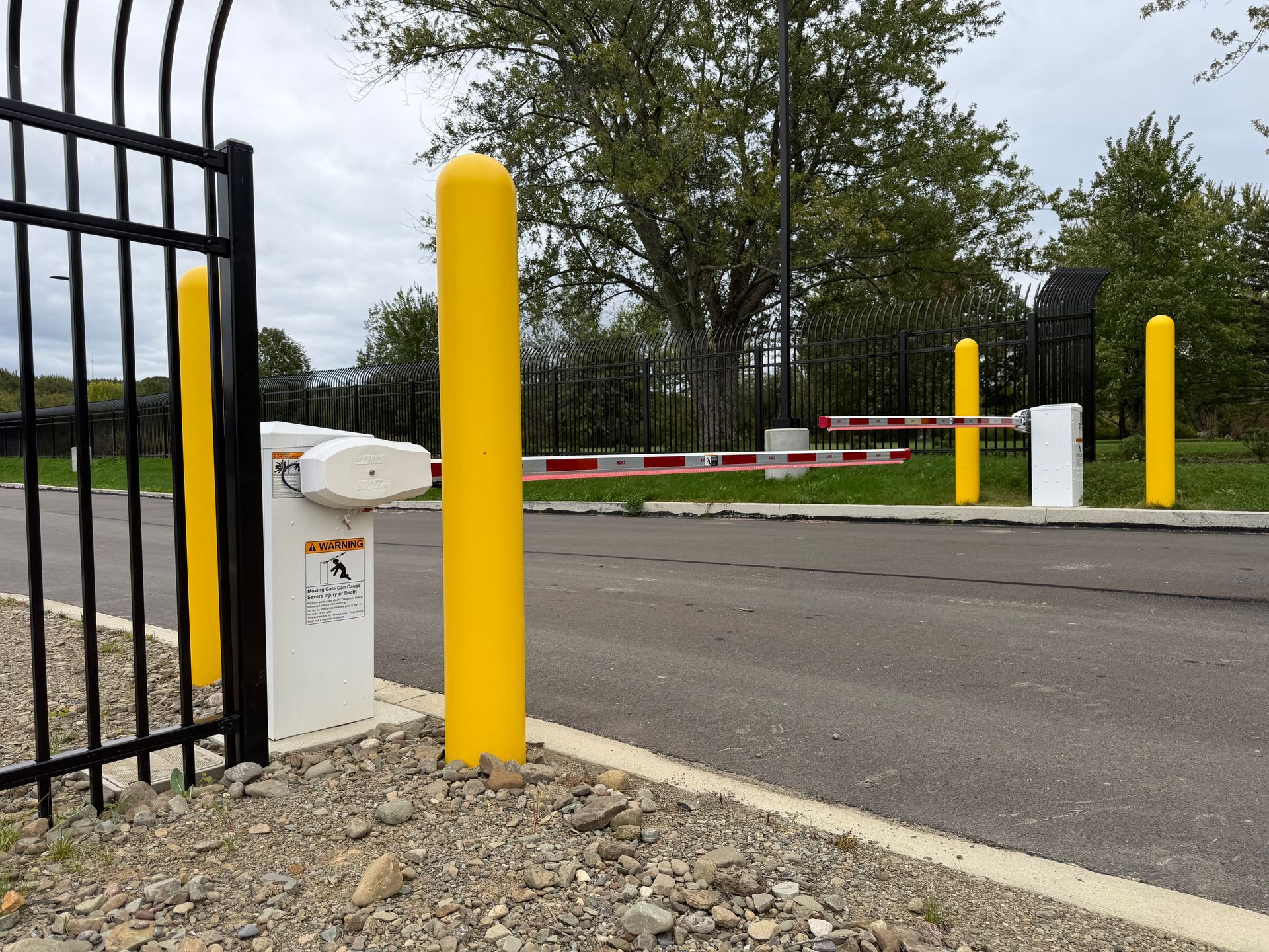 Closed parking gate with yellow bollards and red-and-white barrier across a road