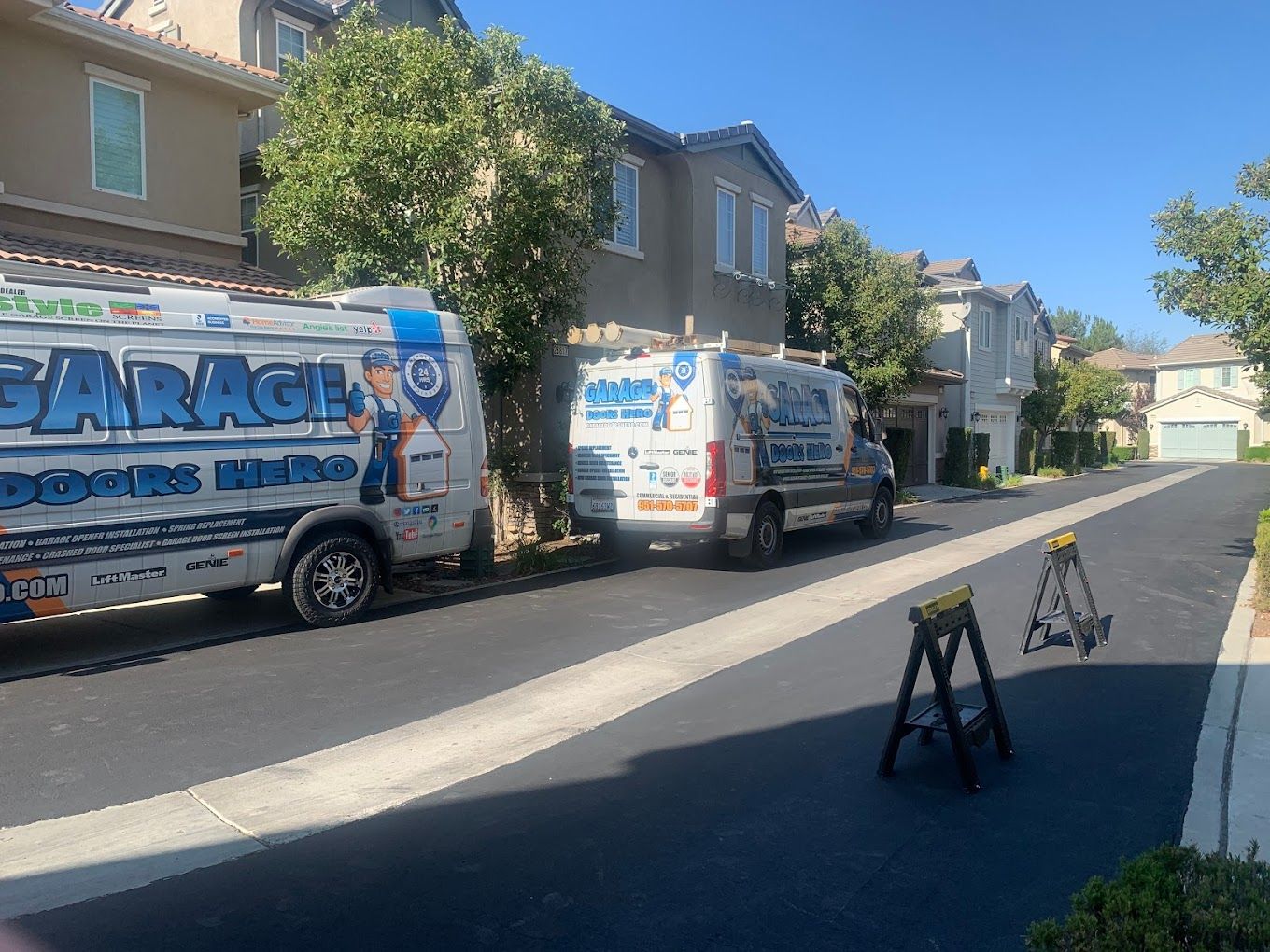 Two vans are parked on the side of the road in front of a house.