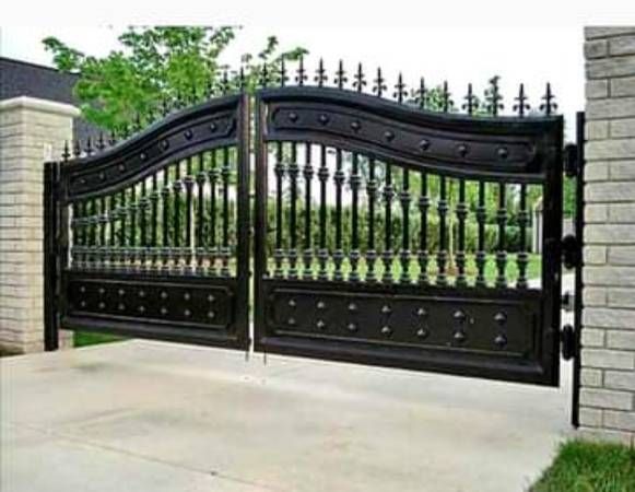 A black wrought iron gate is open to a driveway.