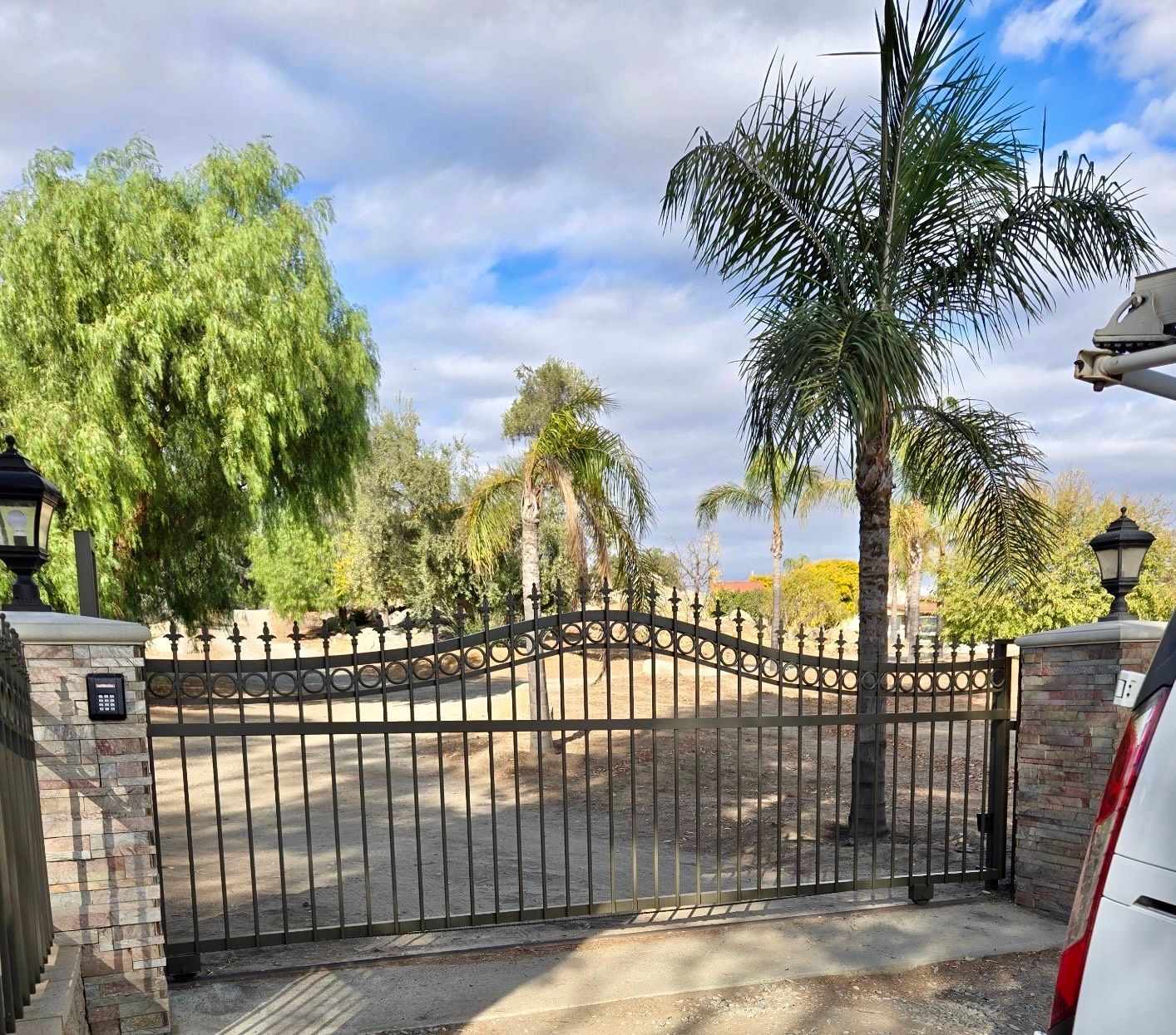 A car is parked in front of a wrought iron gate.