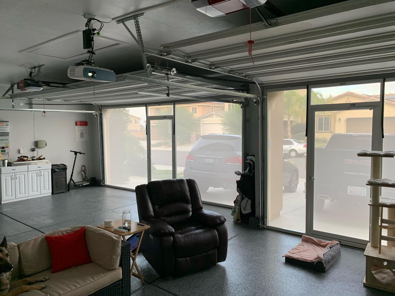 A living room in a garage with a couch , chair , and cat tree.