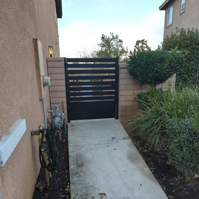 A concrete walkway leading to a black gate