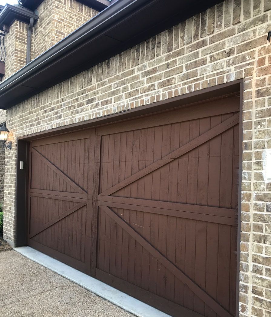 A brown wooden garage door is on a brick building.