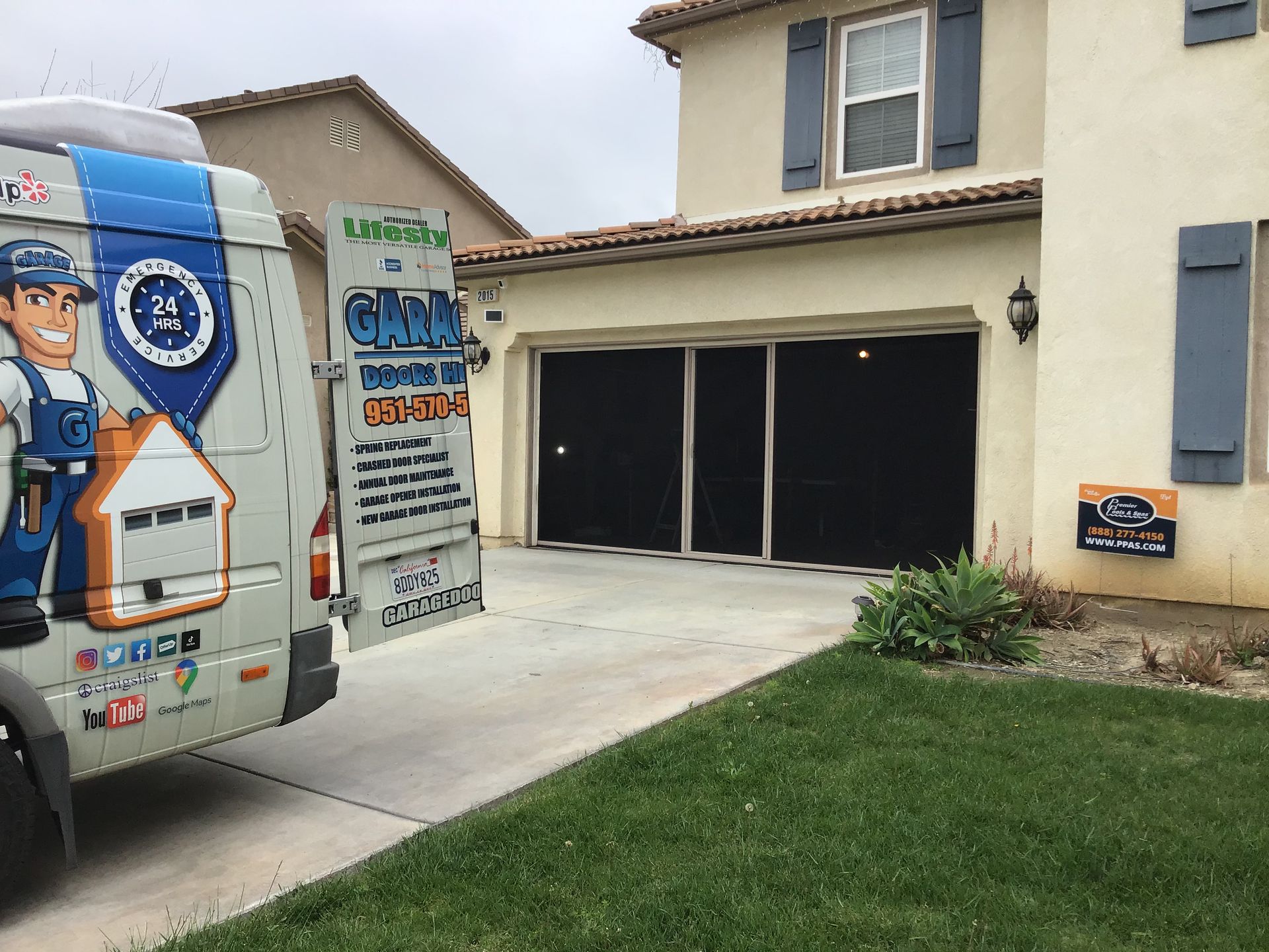 A garage door company van is parked in front of a house