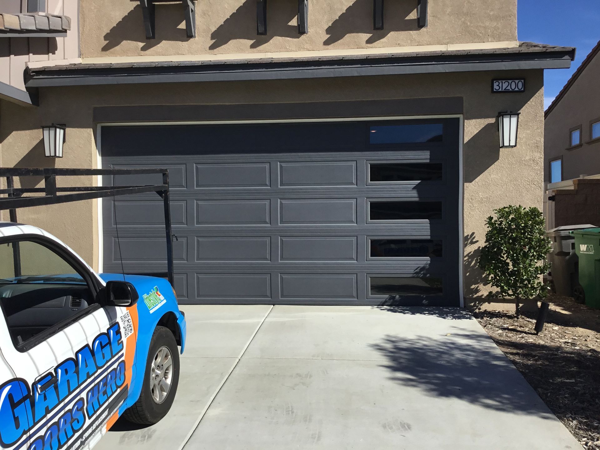 A garage door company truck is parked in front of a garage door.