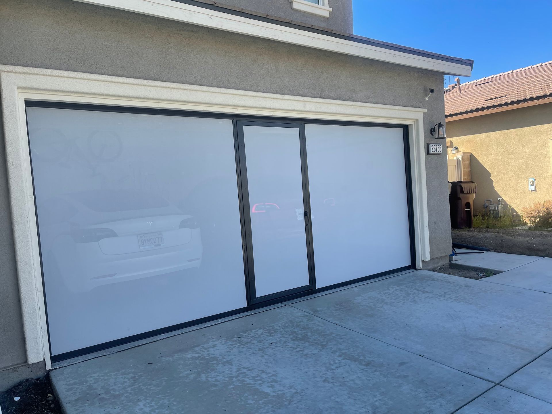 A white garage door is sitting in front of a house.