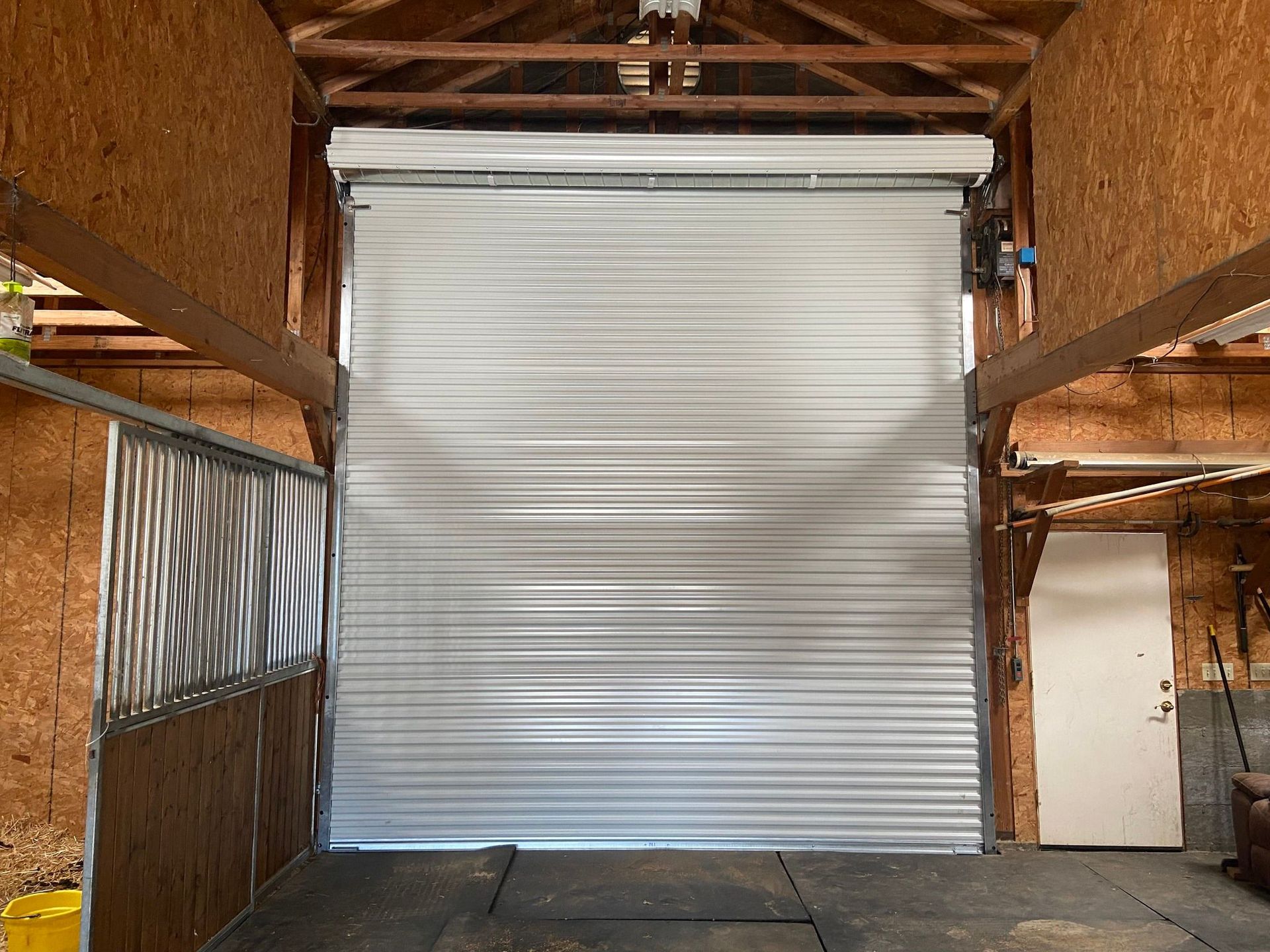 A large garage door is open in a barn.