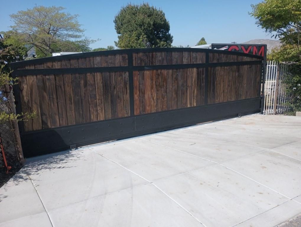 A concrete driveway with a wooden gate in the background