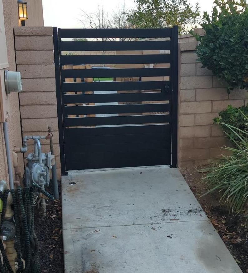 A concrete walkway leading to a black gate