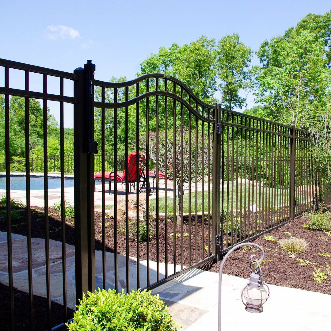 A black wrought iron fence surrounds a swimming pool.