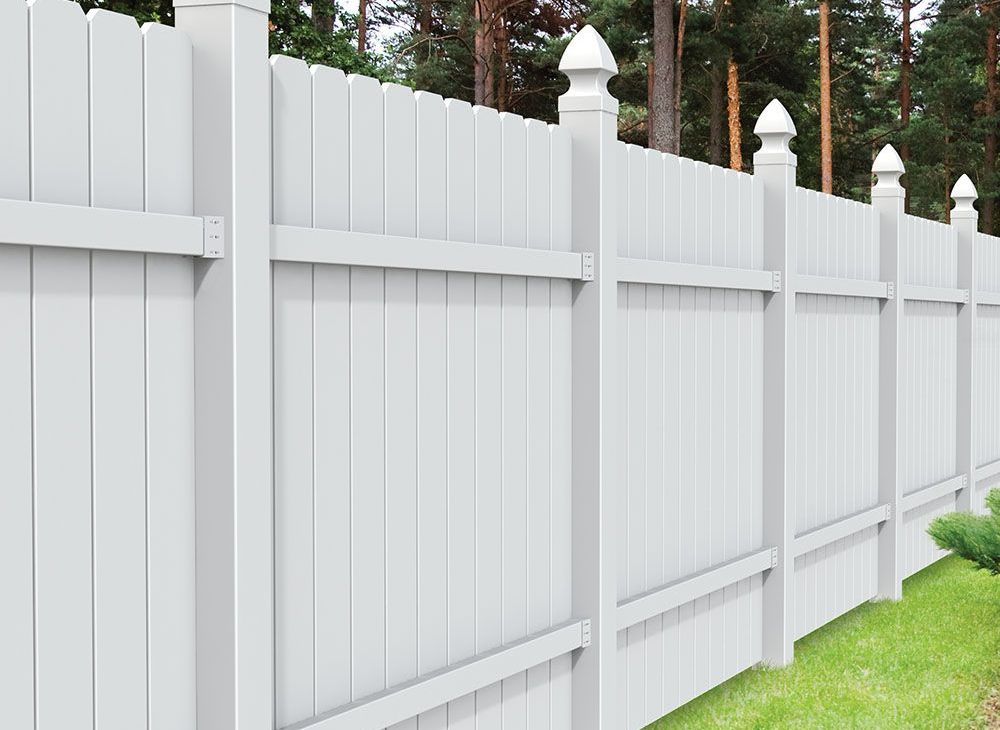 A white vinyl fence is sitting on top of a lush green lawn.