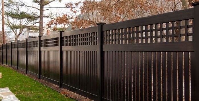 A brown vinyl fence is surrounding a lush green yard.