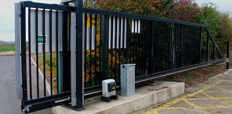 A sliding gate is open to a parking lot.
