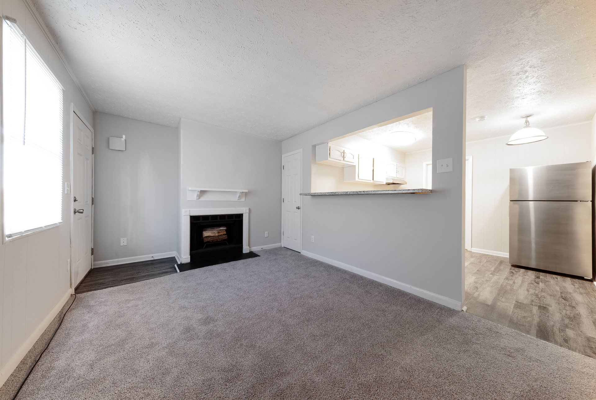 Living room with a fireplace, carpet, and open kitchen pass-through.