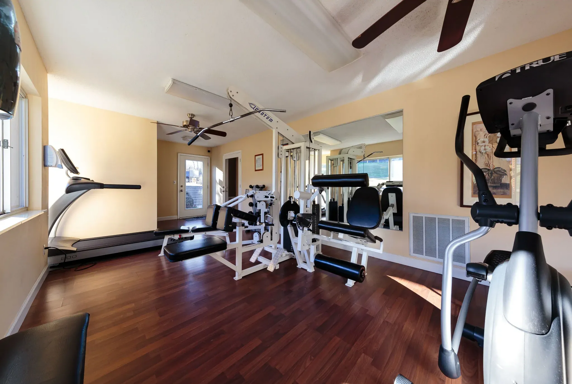Bright on-site gym with treadmill and weight machines.