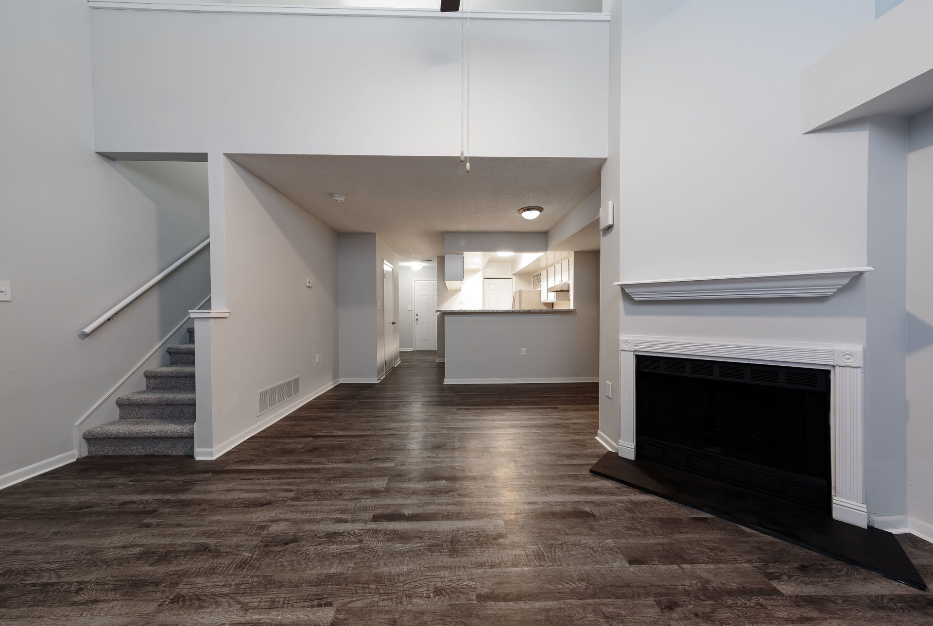 Open-concept living area with stairs, kitchen pass-through, and a fireplace.