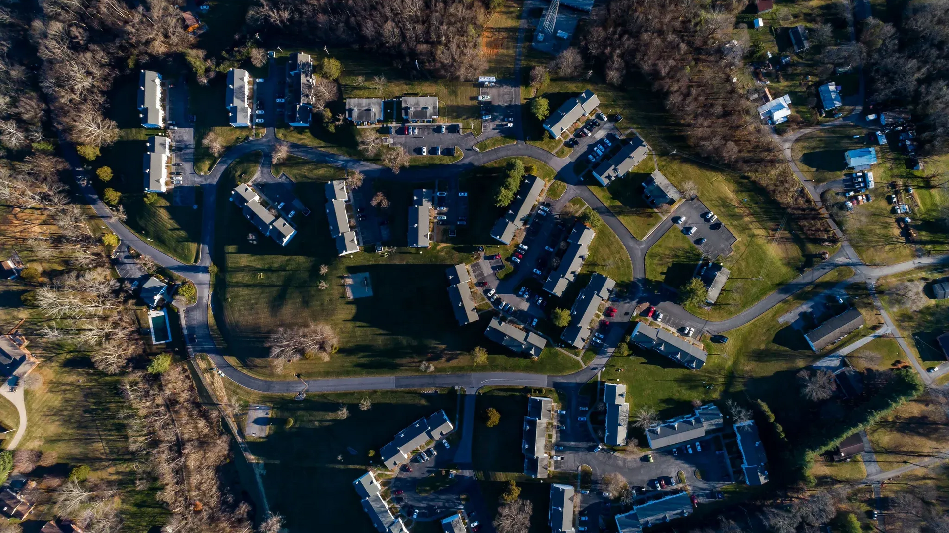 Aerial view of a multifamily apartment community with buildings and winding roads.