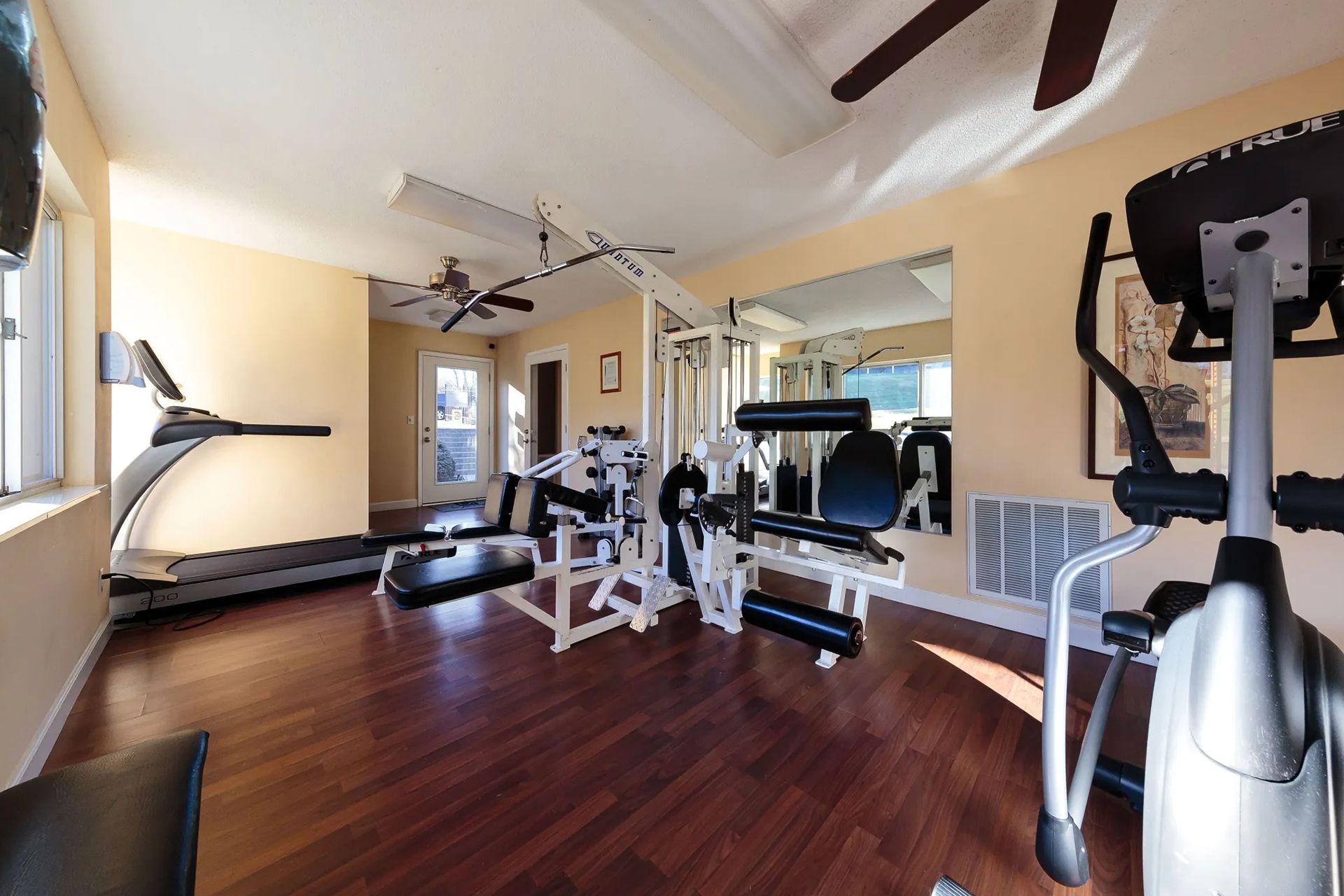 Gym with treadmill, weight machines, elliptical, and dark wood floor at Sterling Hills in Johnson City, TN.