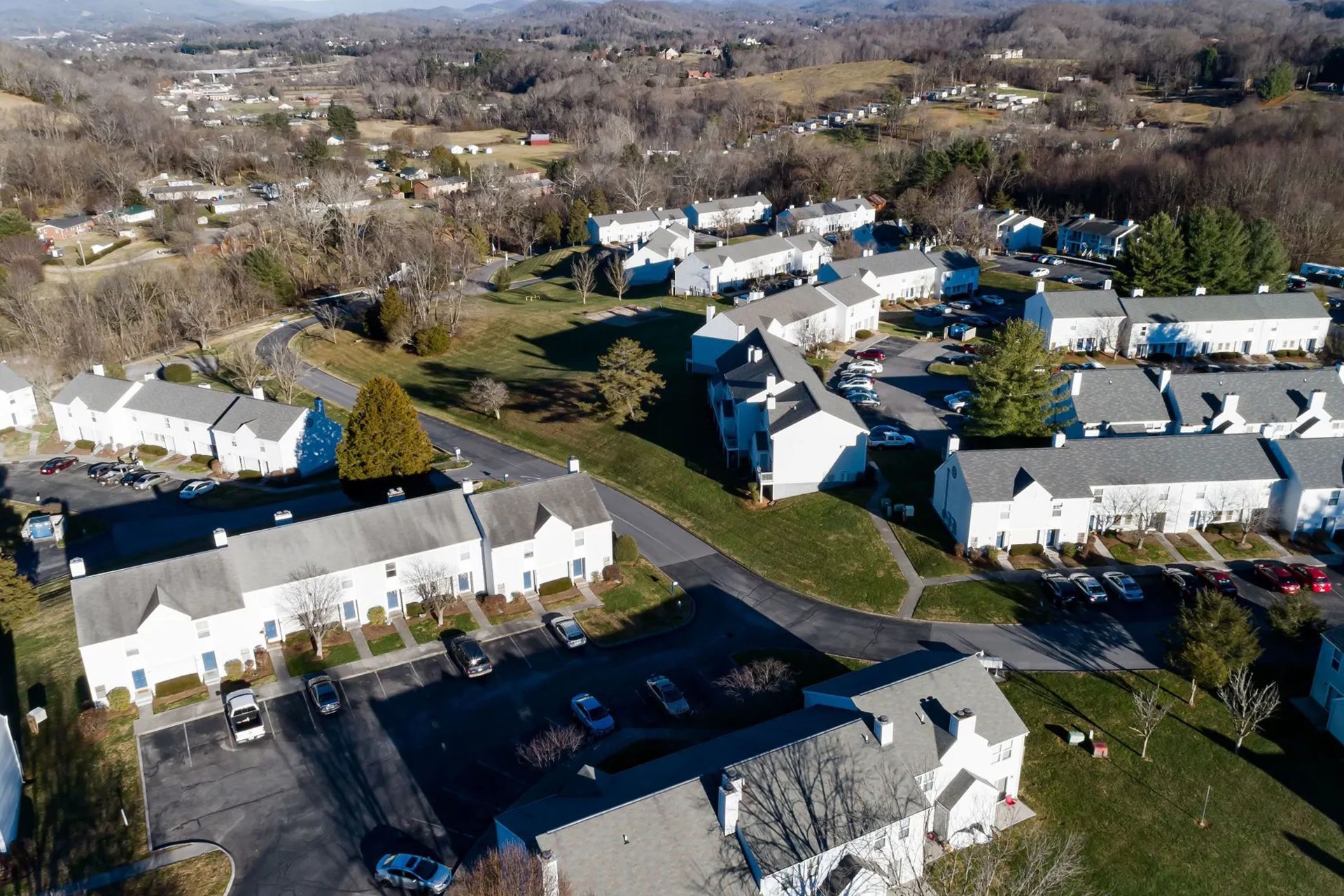 Aerial view of a residential neighborhood with multiple white apartments surrounded by trees and a winding road at Sterling Hills in Johnson City, TN.
