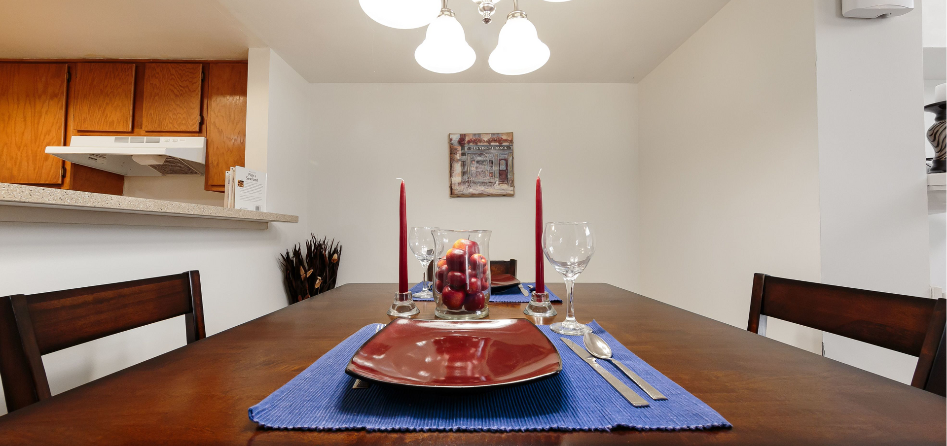 Dining table set with candles and glassware in an apartment dining area.