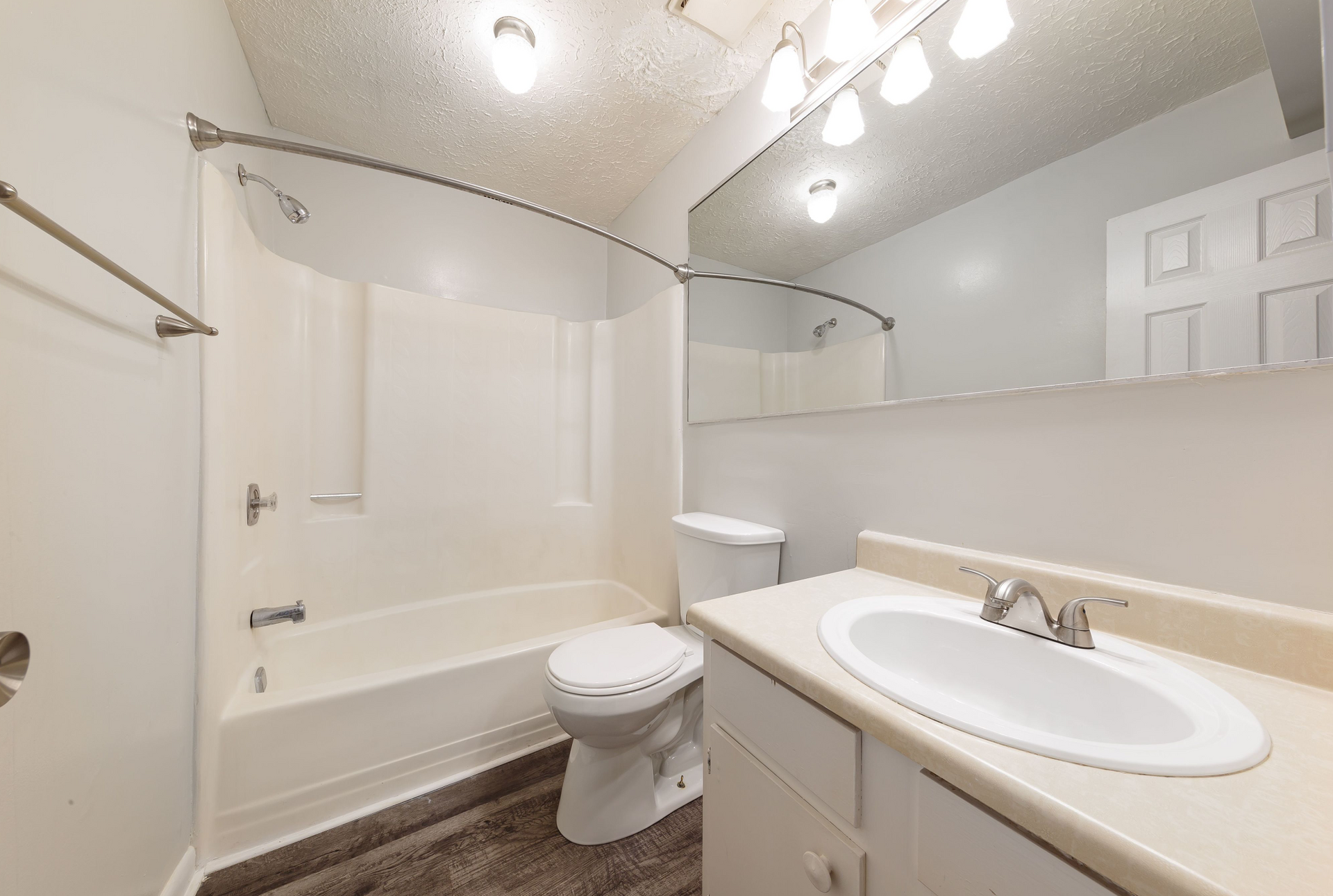 Bathroom with tub/shower, toilet, and a wide vanity with a large mirror.
