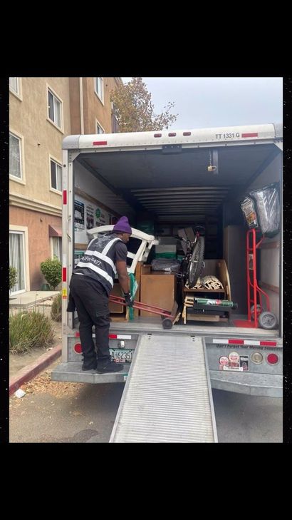 Mover unloading furniture from a truck beside an apartment building