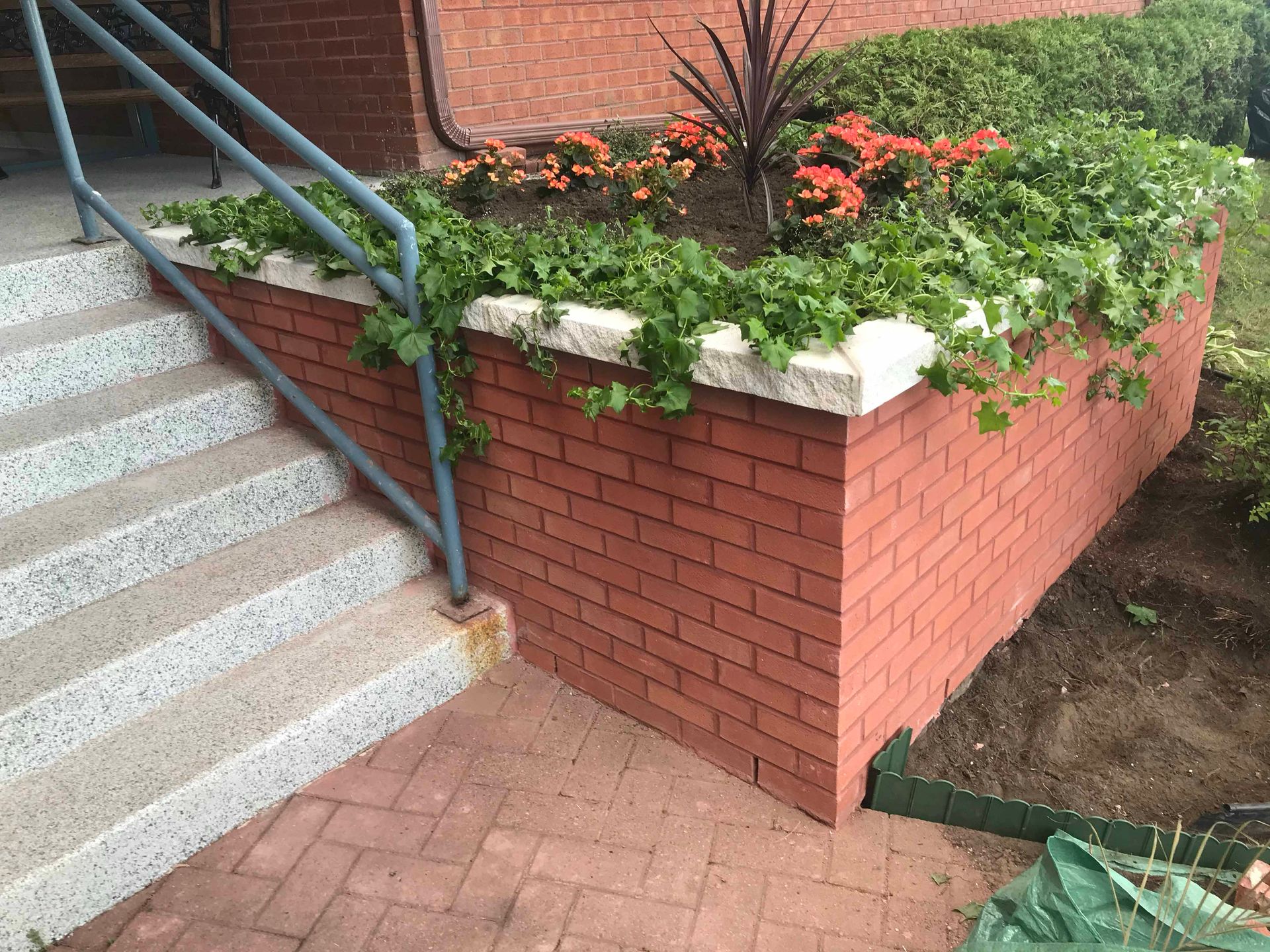 Un mur de briques avec des fleurs à côté d'un escalier.
