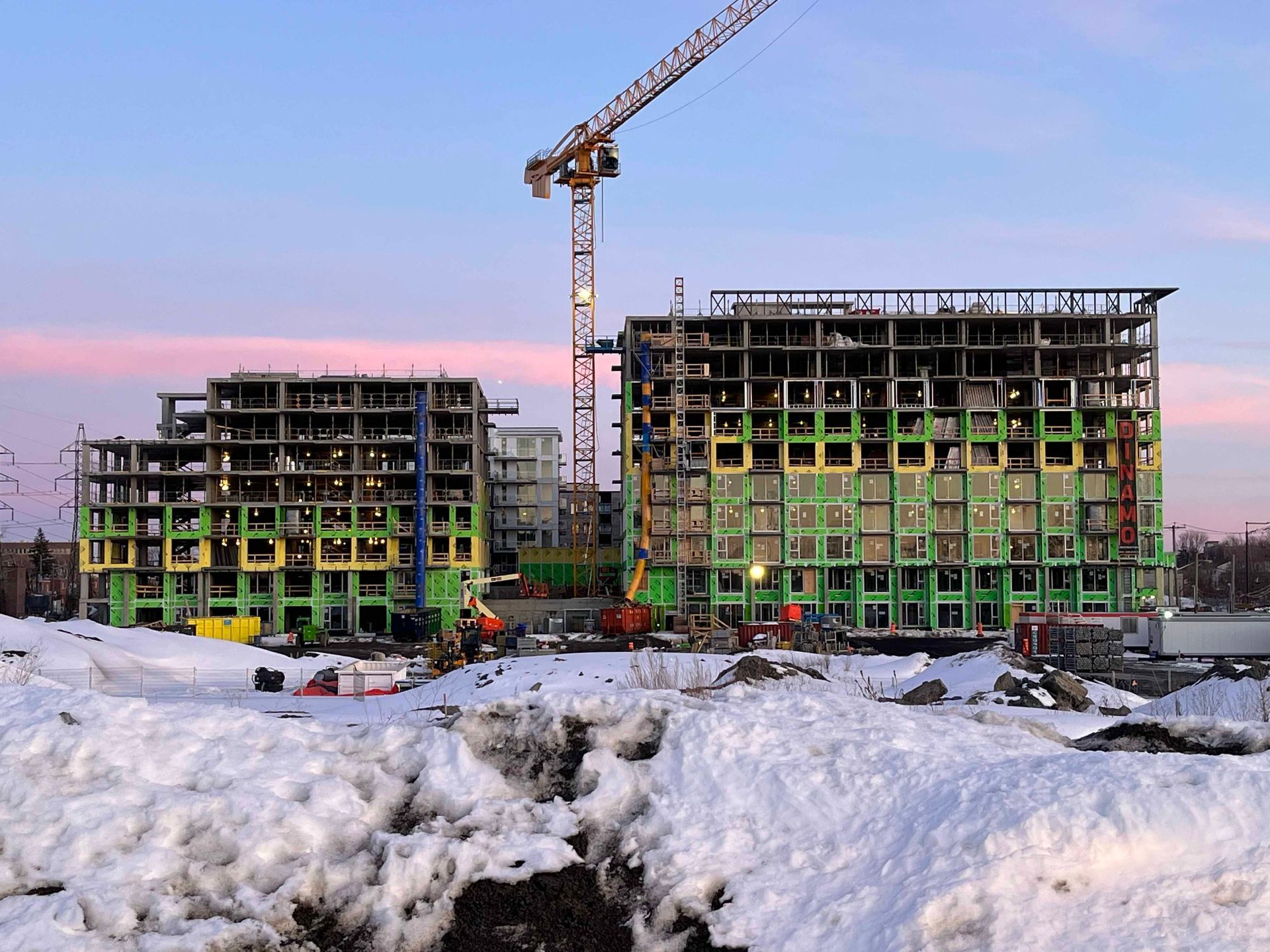 Un grand bâtiment est en construction dans la neige avec une grue en arrière-plan.