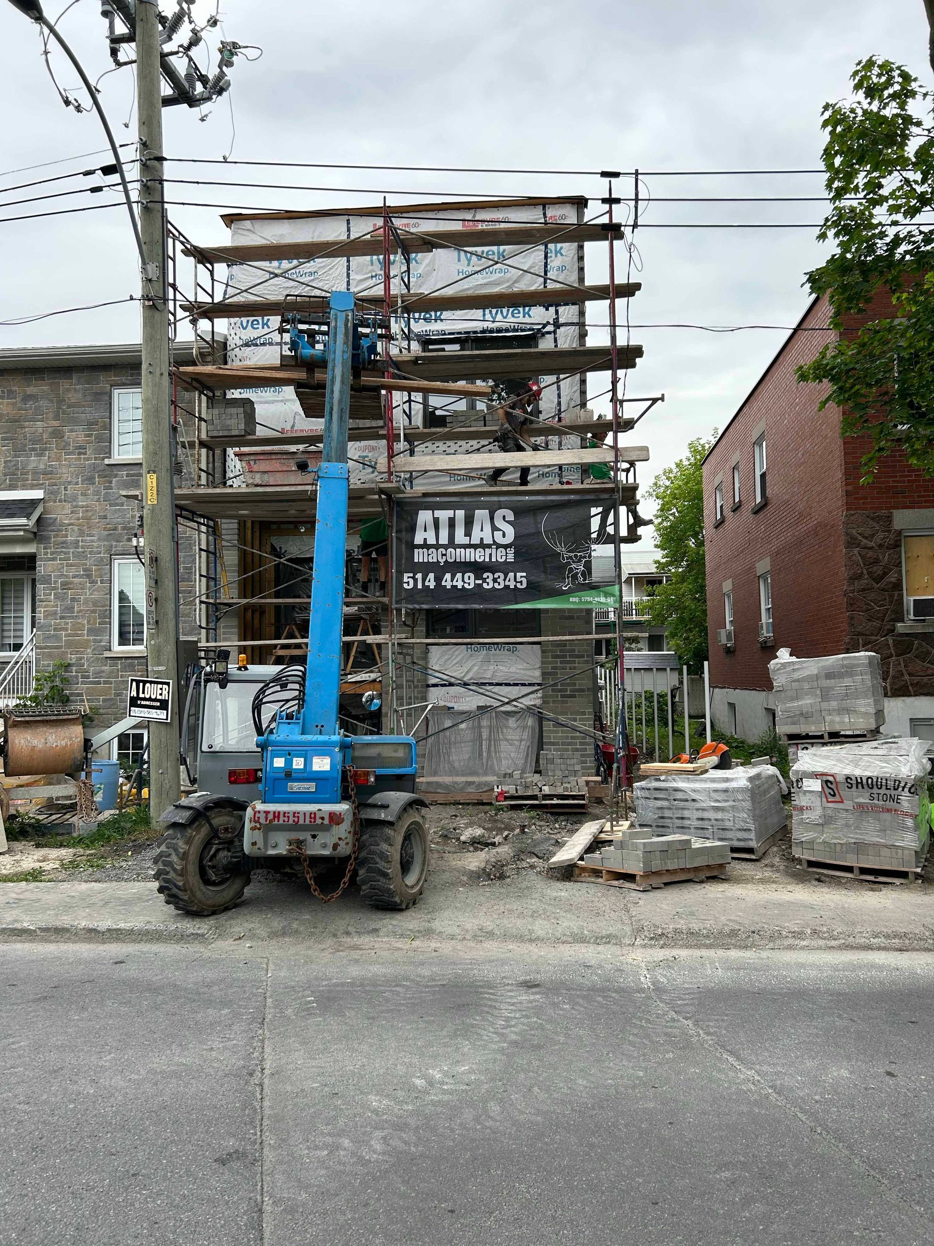 Une grue est assise sur le bord de la route devant un bâtiment en construction.