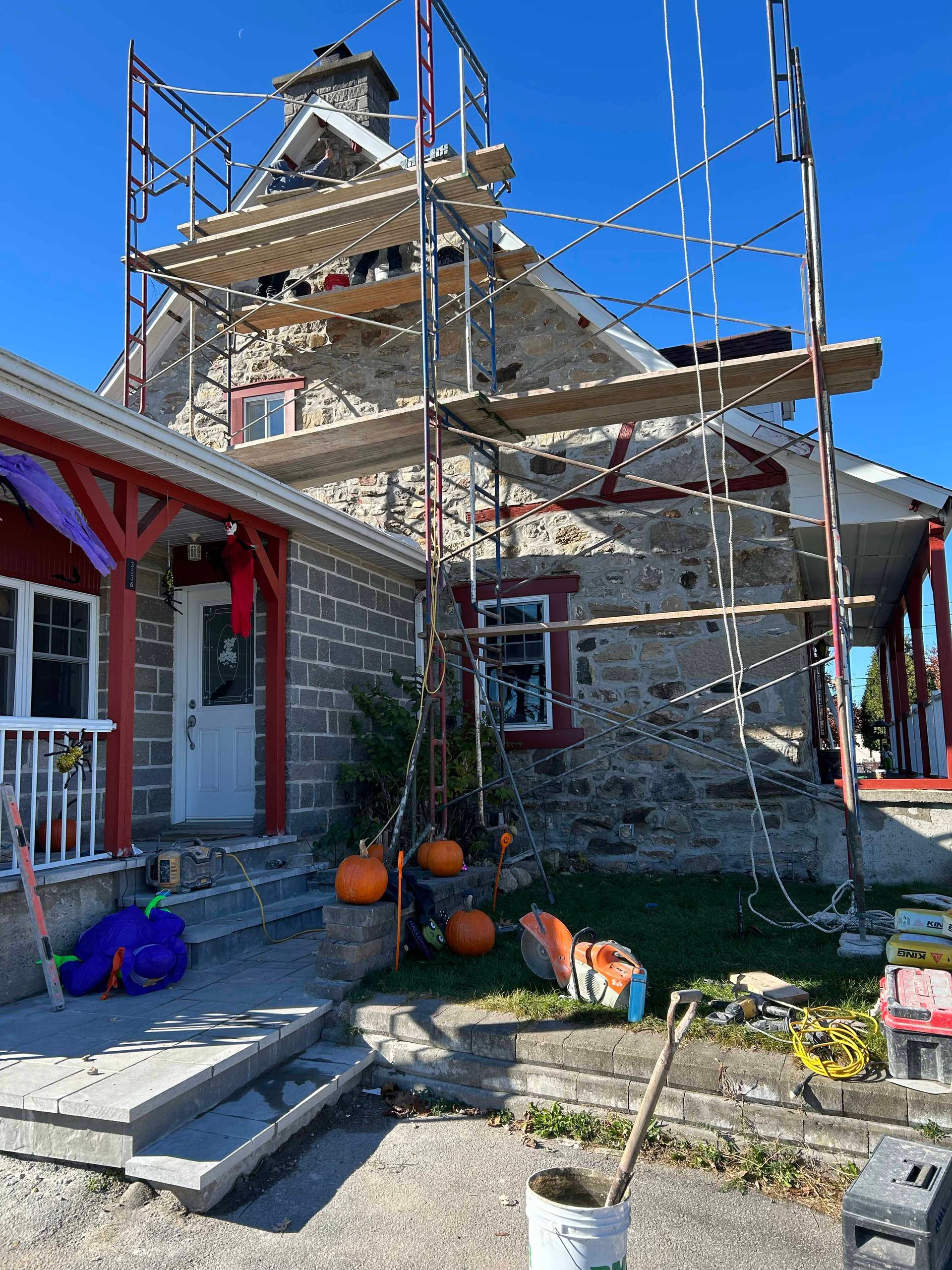 Une maison avec des échafaudages autour et des citrouilles devant.