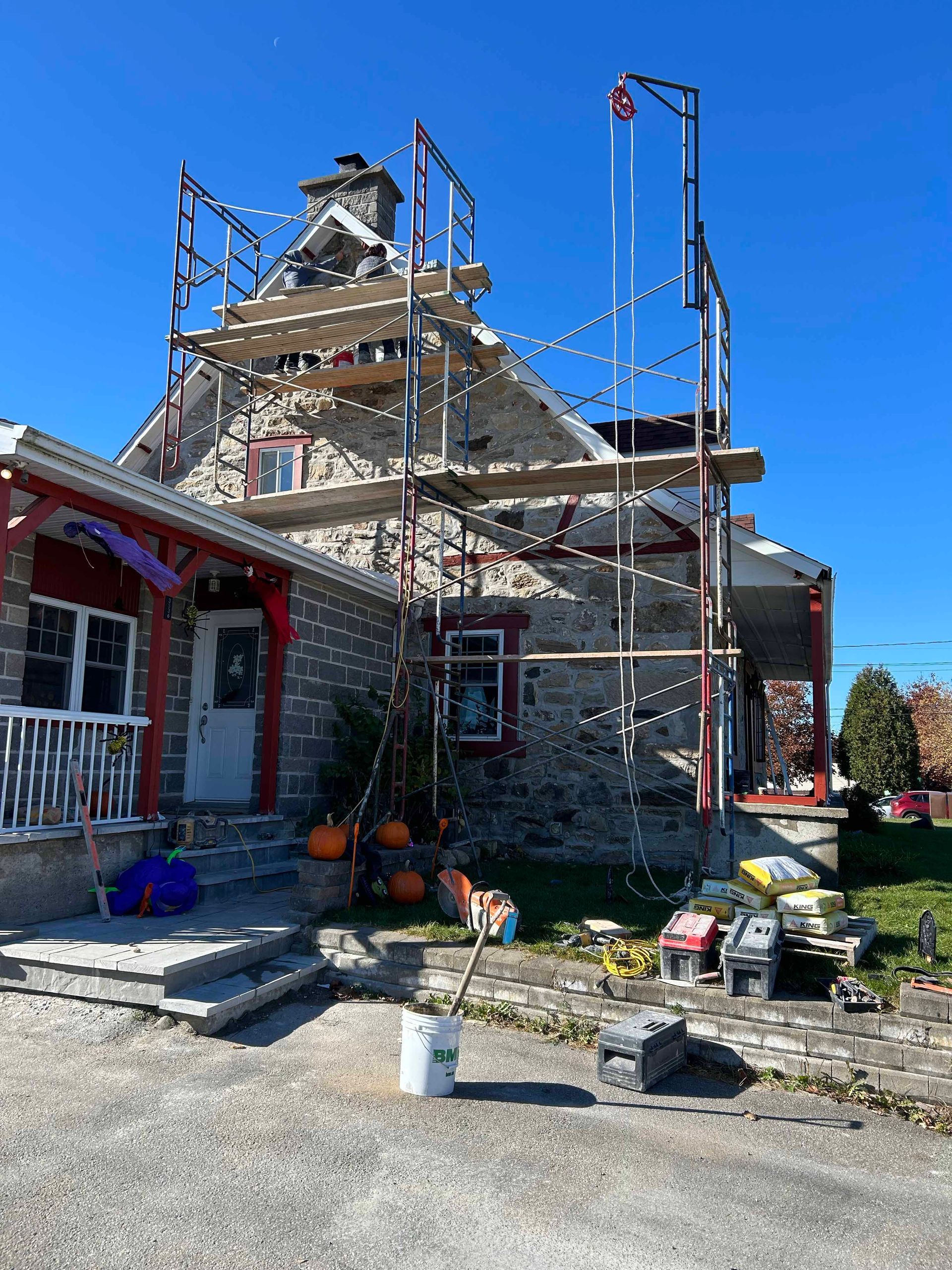 Une maison est en train d'être peinte avec un échafaudage devant elle.