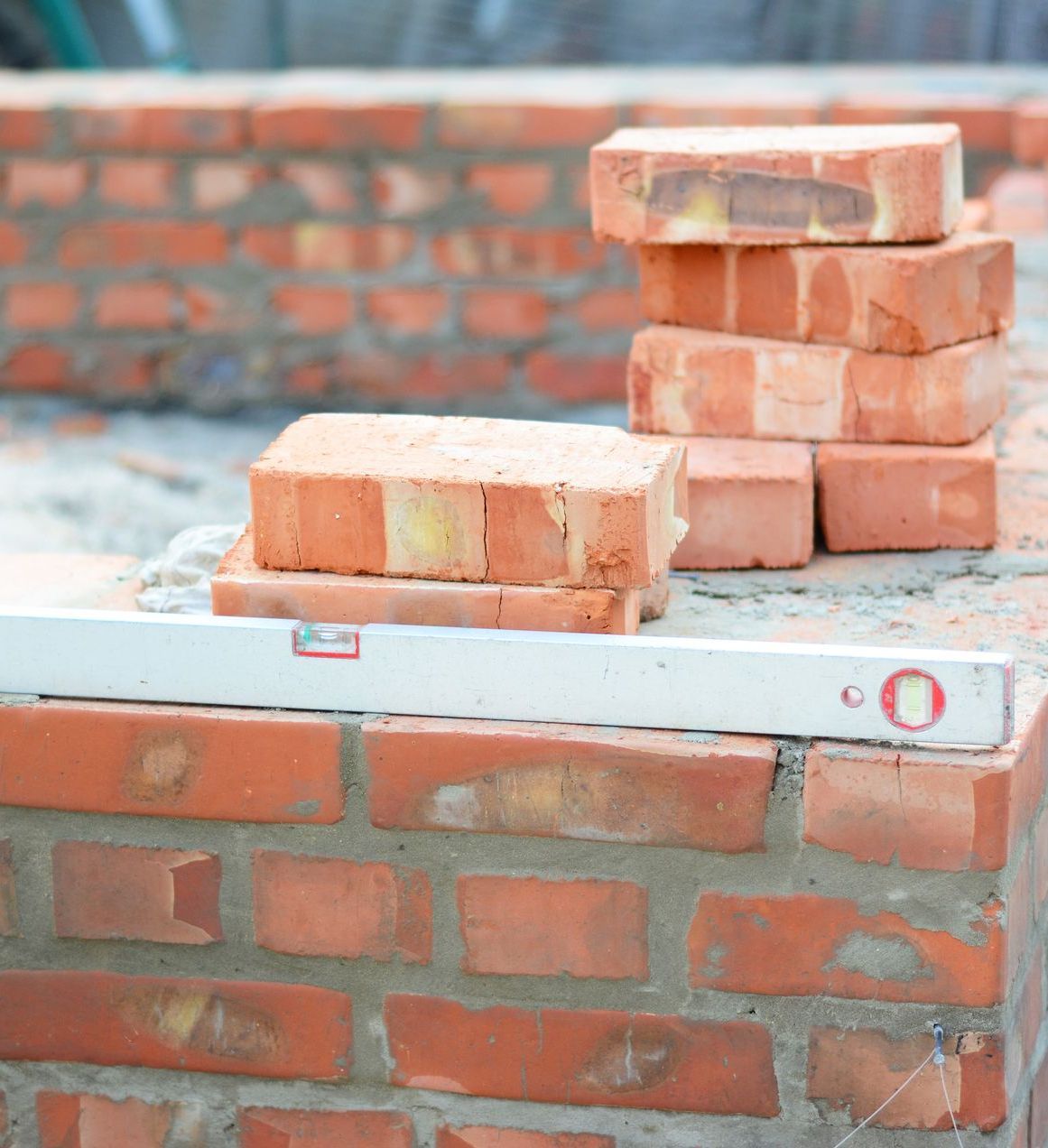 Un mur de briques est en train d'être construit avec des briques et un niveau.