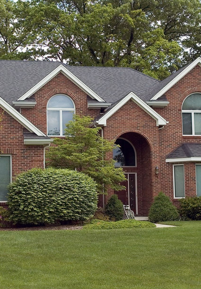 Une grande maison en briques avec une pelouse verte luxuriante devant elle