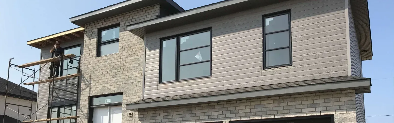 Une grande maison avec beaucoup de fenêtres est en construction.