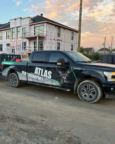 Un camion noir est garé devant un immeuble en construction.