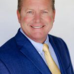 Smiling man in a blue suit with a yellow tie on a white background