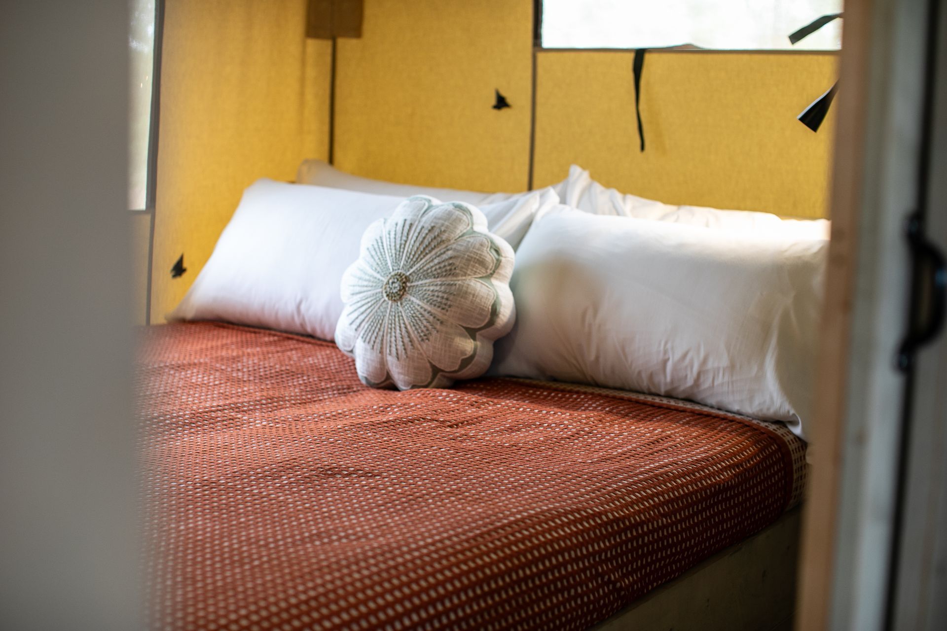 Comfortable queen size bed with decorative pillows inside a canvas cabin at clay cosmos glamping resort in Lumpkin, Georgia.