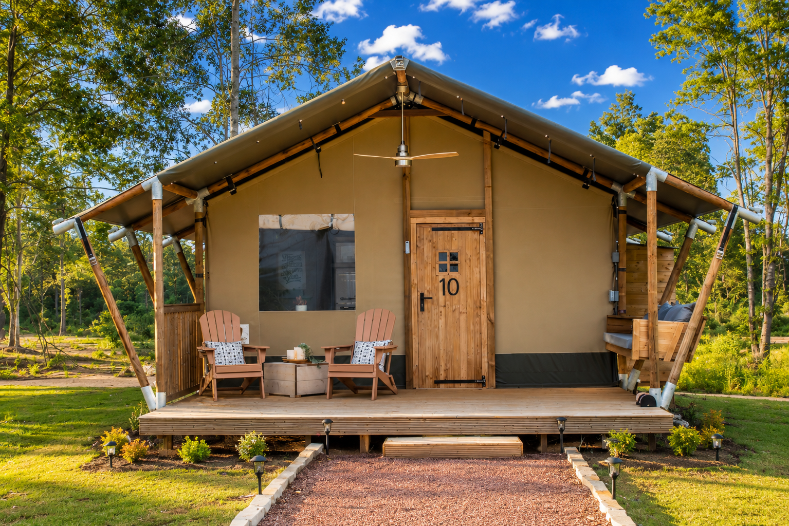 Exterior of Canvas Cabin at Clay Cosmos glamping resort in Lumpkin Georgia with outdoor seats on front porch and a sunny sky.