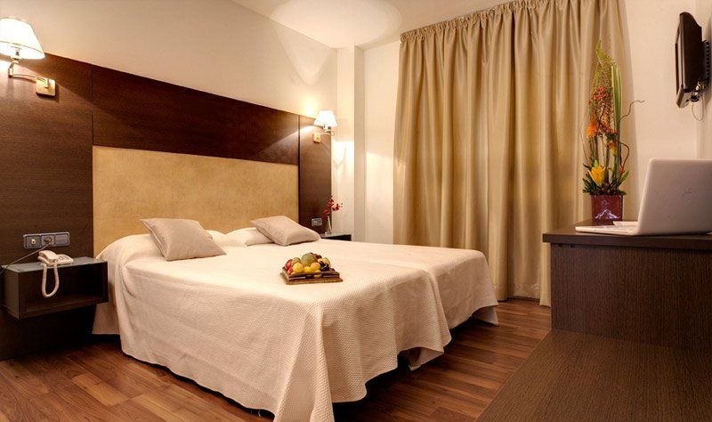 Una habitación de hotel con dos camas y una computadora portátil en el escritorio.