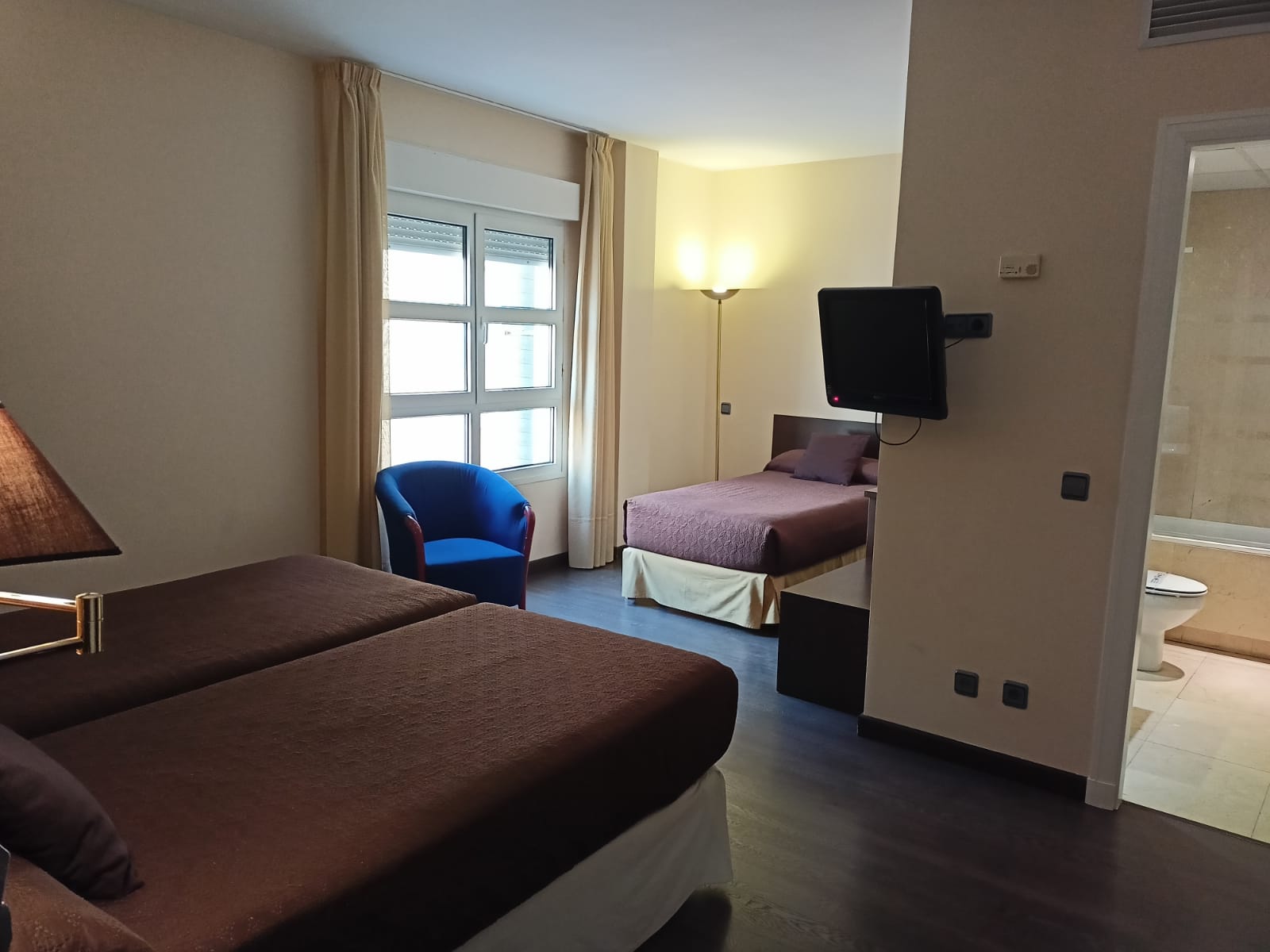 Una habitación de hotel con dos camas, una silla y una televisión.