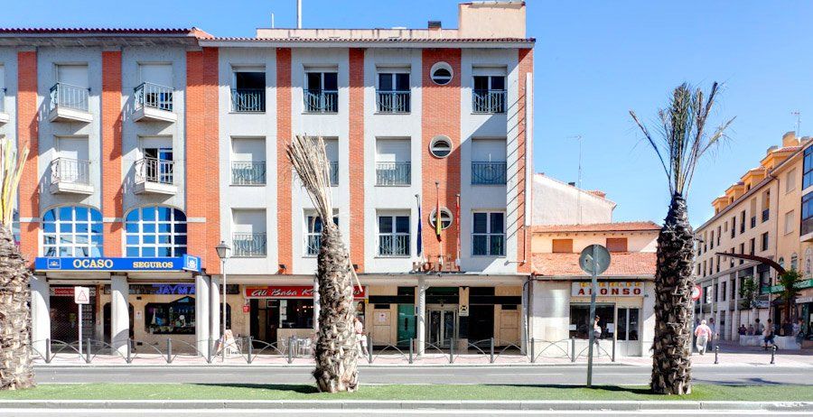 Un edificio grande con muchas ventanas y palmeras en el frente.