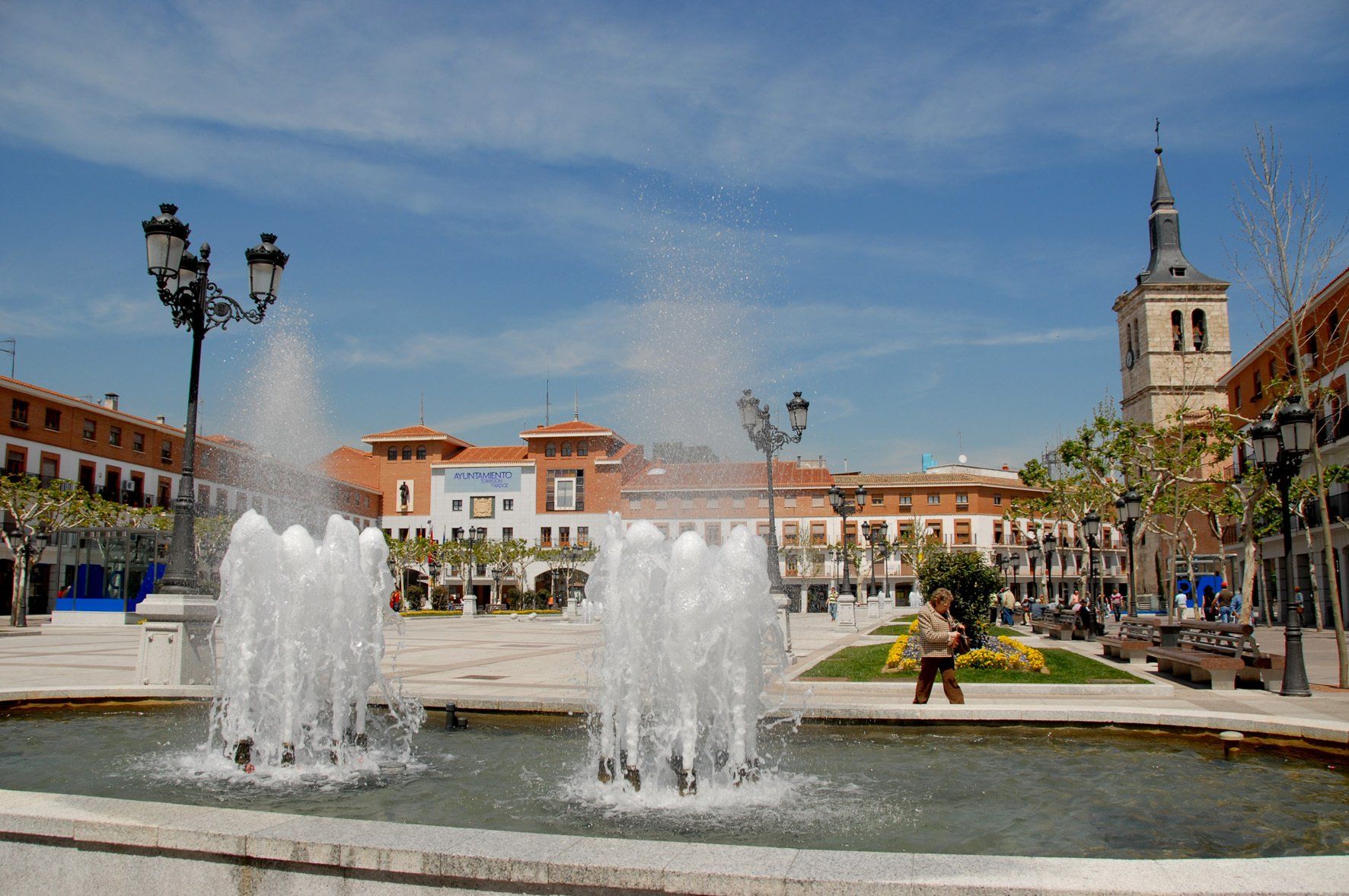 Una fuente en un parque con una torre de reloj al fondo.