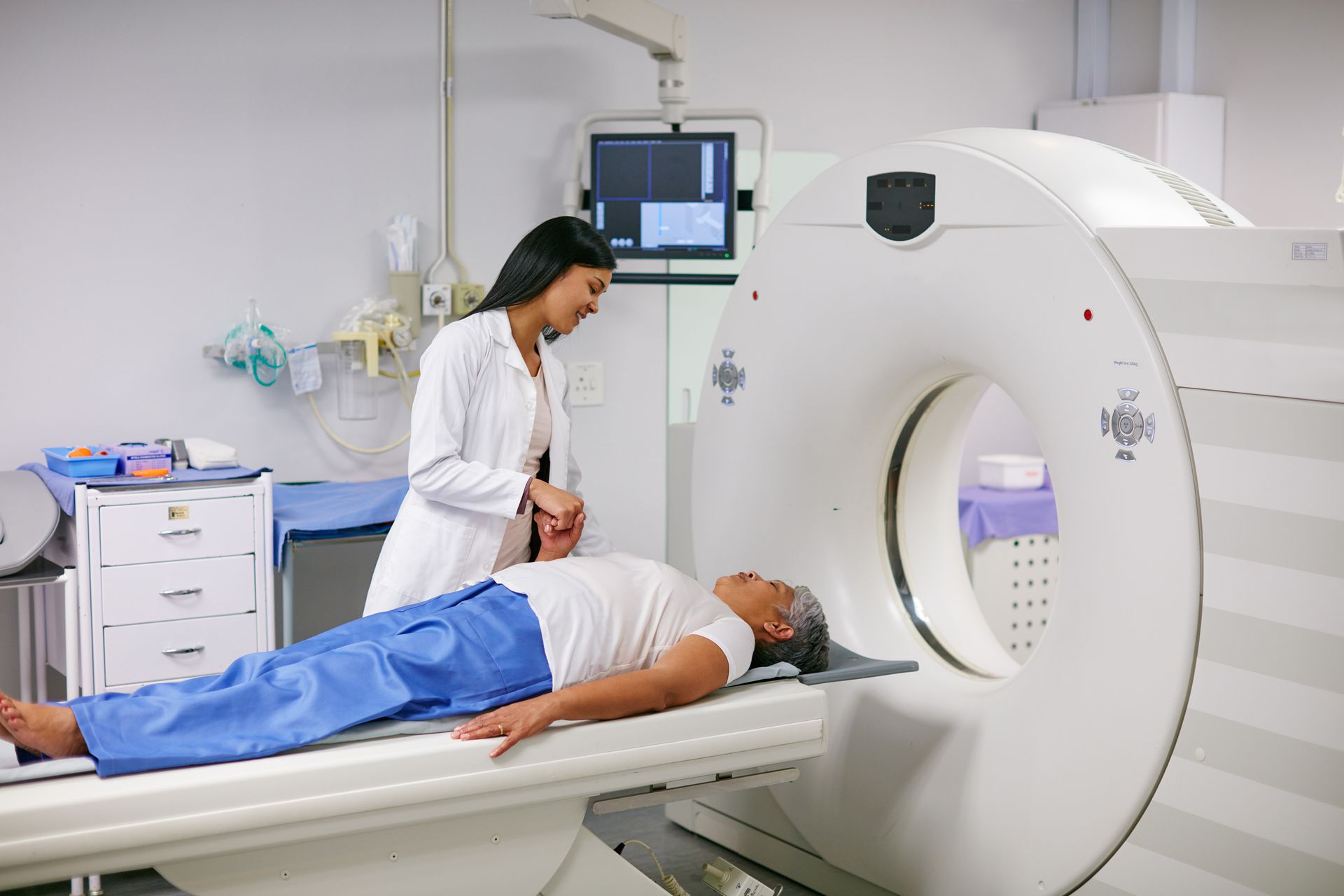 A doctor is holding a patient’s hand before getting an MRI.