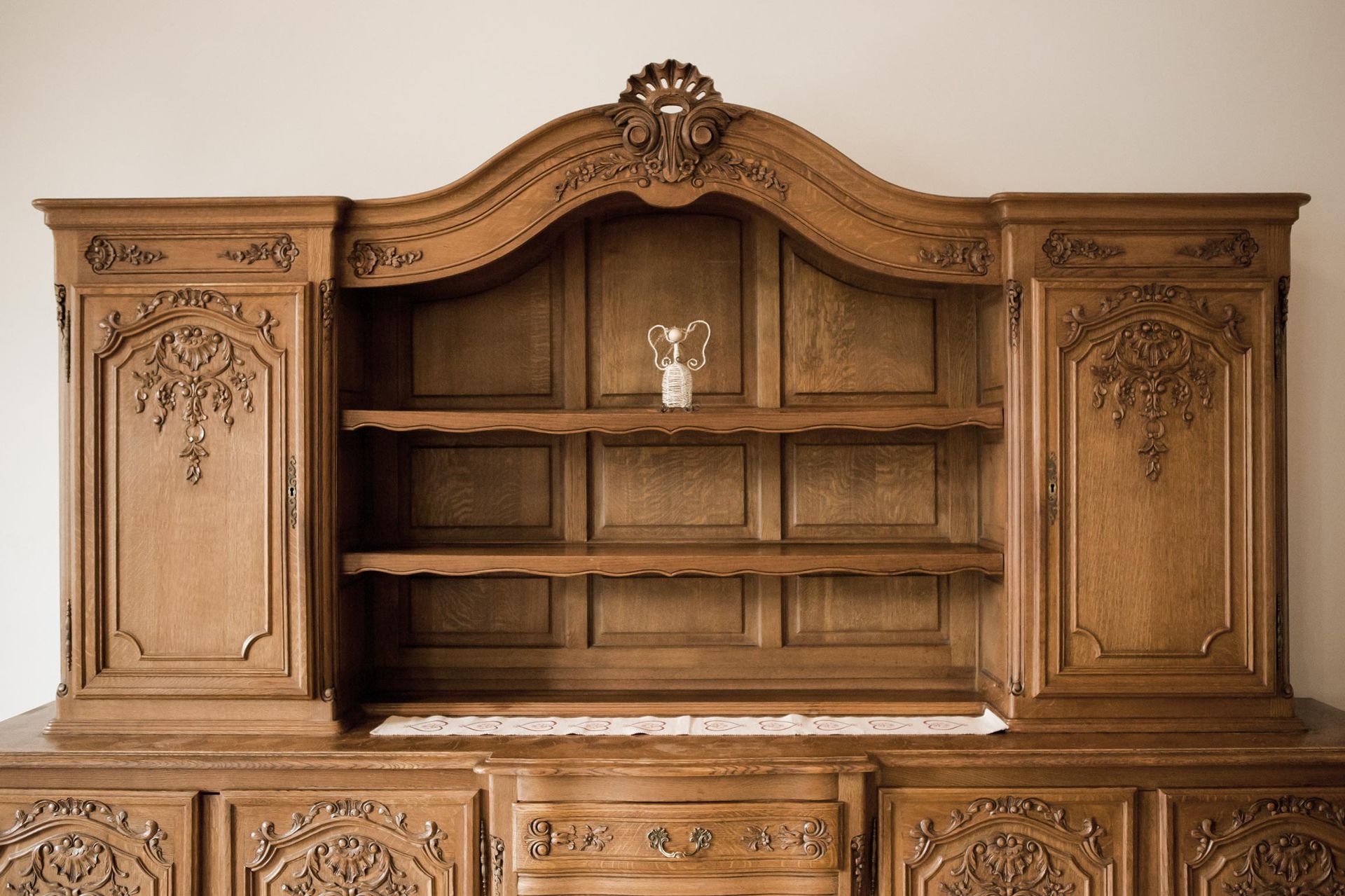 Wooden antique cabinet with ornate carvings and a small trophy on a shelf.