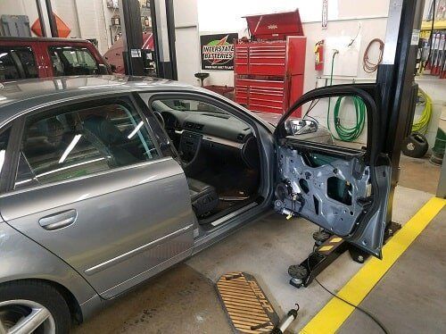 A car is sitting on a lift in a garage with its doors open.